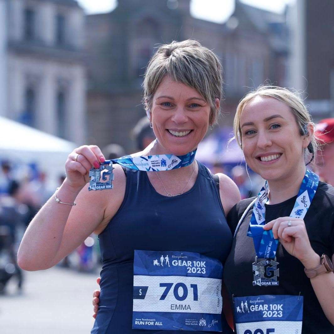 Two runners hold their medals with pride