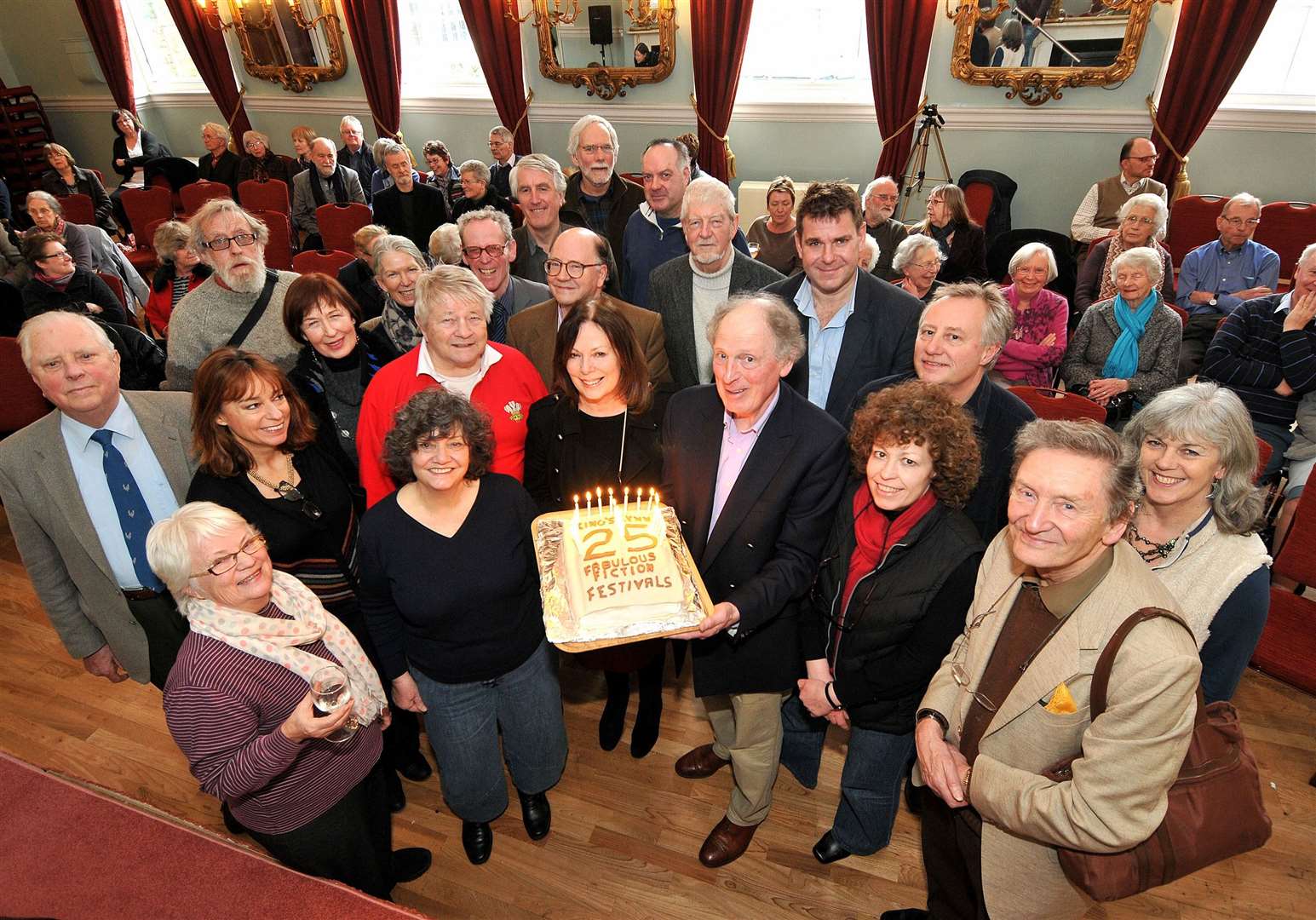 King's Lynn Fiction Festival chairman Tony Ellis holding a 25th celebration cake in 2013 surrounded by authors and the committee