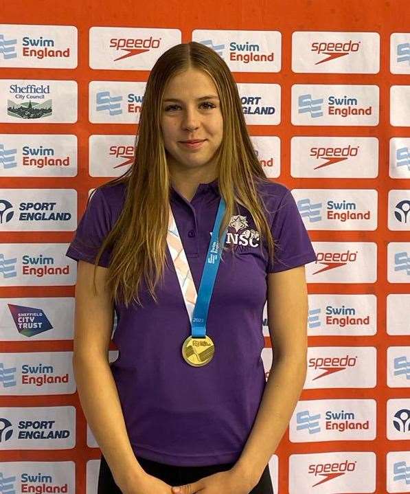 Millie Harris proudly displays her gold medal for the 50m butterfly.