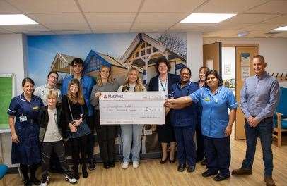 Sisters Jodie and Chloe Tawn present the cheque for £4,000 to the Macmillan Ward at the QEH in memory of their mum Janet.