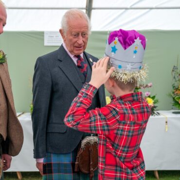 Schoolboy tries on prize-winning cardboard crown in front of the King