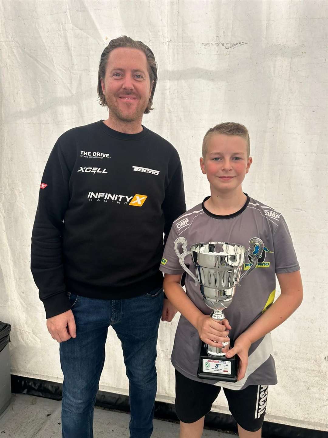 Jenson Sayell shows off his third-place trophy from round 10 with InfinityX Steve Cumber, supplier of race oils and Greyhound seat.
