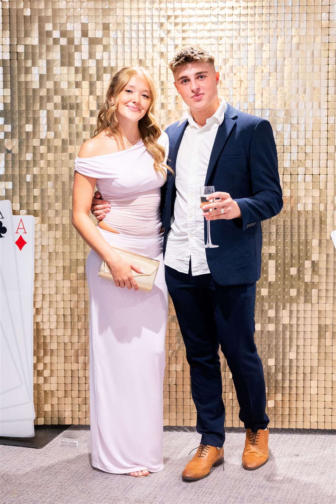 Two students posing in front of sequinned wall at prom